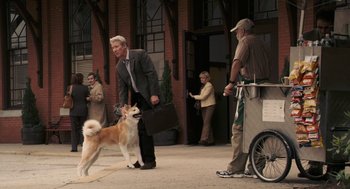 Movie still from “Hachi: A Dog's Tale” (2009), directed by Lasse Hallström – A man in a business suit is walking a dog in the street; Wide shot, Over the shoulder angle