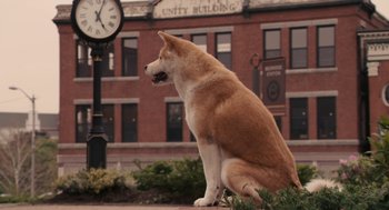 Movie still from “Hachi: A Dog's Tale” (2009), directed by Lasse Hallström – A large brown and white dog sitting next to a clock tower; Wide shot, High angle
