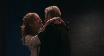 Movie still from “Hachi: A Dog's Tale” (2009), directed by Lasse Hallström – A woman is holding a man's face in a dark room; Medium shot, Low angle