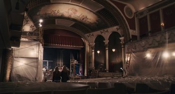 Movie still from “Hachi: A Dog's Tale” (2009), directed by Lasse Hallström – Two people sitting on the stage of an old theater; Extreme Wide shot, Low angle