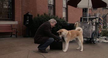 Movie still from “Hachi: A Dog's Tale” (2009), directed by Lasse Hallström – A man kneeling down next to a brown and white dog; Wide shot, High angle