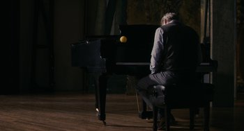 Movie still from “Hachi: A Dog's Tale” (2009), directed by Lasse Hallström – A man sitting in front of a black piano; Wide shot, Over the shoulder angle