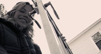 Movie still from “Hachi: A Dog's Tale” (2009), directed by Lasse Hallström – A woman standing in front of a ski lift holding ski poles; Close Up shot, Low angle