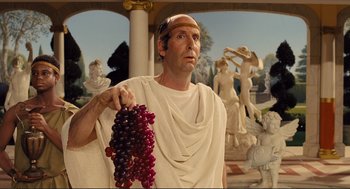 Movie still from “Hail, Caesar!” (2016), directed by Ethan Coen – A man in a toga holding a bunch of grapes; Medium shot, Over the shoulder angle