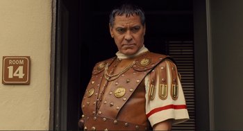 Movie still from “Hail, Caesar!” (2016), directed by Ethan Coen – A man in a roman soldier costume standing in front of a building; Close Up shot, Low angle