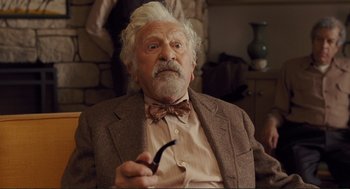 Movie still from “Hail, Caesar!” (2016), directed by Ethan Coen – An old man with a white beard holding a smoking pipe; Close Up shot, Over the shoulder angle