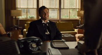 Movie still from “Hail, Caesar!” (2016), directed by Ethan Coen – A man sitting at a table in front of a phone; Medium shot, Low angle
