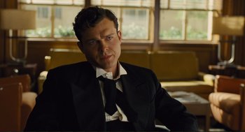 Movie still from “Hail, Caesar!” (2016), directed by Ethan Coen – A man wearing a suit and tie sitting in a chair; Close Up shot, Low angle