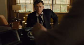 Movie still from “Hail, Caesar!” (2016), directed by Ethan Coen – A man sitting at a table in front of a camera; Medium shot, Low angle