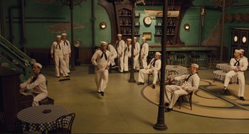 Movie still from “Hail, Caesar!” (2016), directed by Ethan Coen – A group of men in white uniforms are standing in a room; Wide shot, High angle