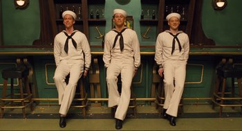 Movie still from “Hail, Caesar!” (2016), directed by Ethan Coen – A group of three sailors sitting in a row; Wide shot, Low angle
