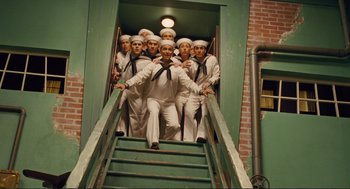 Movie still from “Hail, Caesar!” (2016), directed by Ethan Coen – A group of men in sailor outfits standing on a set of stairs; Wide shot, Low angle