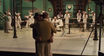 Movie still from “Hail, Caesar!” (2016), directed by Ethan Coen – A couple of people that are hugging on a stage; Wide shot, Over the shoulder angle