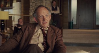 Movie still from “Hail, Caesar!” (2016), directed by Ethan Coen – An older man wearing a suit and tie sitting in front of a fireplace; Close Up shot, Over the shoulder angle