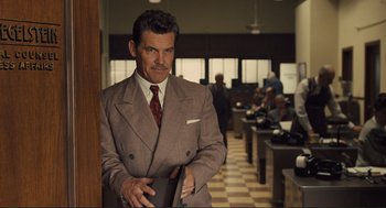 Movie still from “Hail, Caesar!” (2016), directed by Ethan Coen – A man in a suit and tie standing in an office; Medium shot, Over the shoulder angle