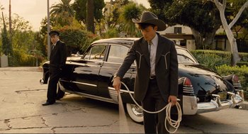 Movie still from “Hail, Caesar!” (2016), directed by Ethan Coen – A man in a cowboy hat holding a whip; Wide shot, Low angle