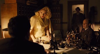 Movie still from “Hail, Caesar!” (2016), directed by Ethan Coen – A woman standing in front of a table with chess pieces on top of it; Medium shot, Over the shoulder angle