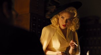 Movie still from “Hail, Caesar!” (2016), directed by Ethan Coen – A woman with blonde curly hair is smoking a cigarette; Medium shot, Over the shoulder angle
