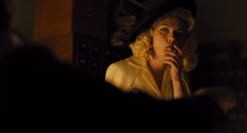 Movie still from “Hail, Caesar!” (2016), directed by Ethan Coen – A woman smoking a cigarette in a dimly - lit room; Medium shot, Low angle