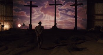 Movie still from “Hail, Caesar!” (2016), directed by Ethan Coen – A man standing in front of three crosses at sunset; Wide shot, Low angle