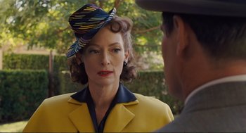 Movie still from “Hail, Caesar!” (2016), directed by Ethan Coen – An older woman wearing a hat and a yellow jacket; Close Up shot, Over the shoulder angle