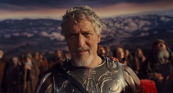 Movie still from “Hail, Caesar!” (2016), directed by Ethan Coen – An older man wearing a silver armor stands in front of a group of people; Close Up shot, Low angle