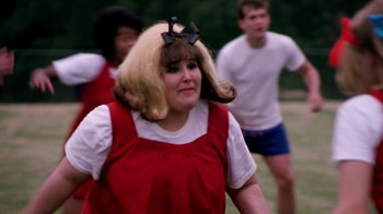 Movie still from “Hairspray” (1988), directed by John Waters – A woman in a red dress with a black bow on her head; Close Up shot, Over the shoulder angle