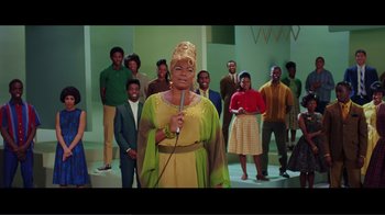 Movie still from “Hairspray” (2007), directed by Adam Shankman – An older woman holding a microphone in front of a group of people; Medium shot, Low angle