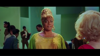 Movie still from “Hairspray” (2007), directed by Adam Shankman – A woman in a yellow and green dress and a gold head piece; Medium shot, Low angle
