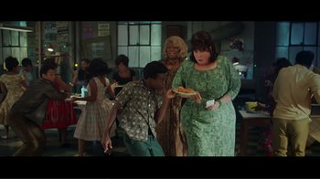 Movie still from “Hairspray” (2007), directed by Adam Shankman – A group of people standing in a room with food on a plate; Medium shot, High angle
