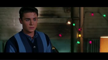 Movie still from “Hairspray” (2007), directed by Adam Shankman – A young man standing in front of christmas lights; Medium shot, Over the shoulder angle