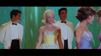 Movie still from “Hairspray” (2007), directed by Adam Shankman – A woman in a yellow dress standing next to a man in a tuxedo; Medium shot, Low angle