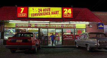 Movie still from “Half Baked” (1998), directed by Tamra Davis – A man standing in front of a convenience store at night; Extreme Wide shot, High angle