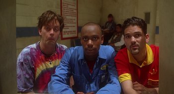 Movie still from “Half Baked” (1998), directed by Tamra Davis – A group of men sitting next to each other in a room; Medium shot, Low angle