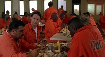 Movie still from “Half Baked” (1998), directed by Tamra Davis – A group of men in orange jumpsuits eating at a table; Medium shot, High angle
