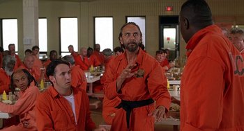Movie still from “Half Baked” (1998), directed by Tamra Davis – A group of men in orange jumpsuits in a room; Medium shot, Over the shoulder angle
