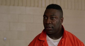 Movie still from “Half Baked” (1998), directed by Tamra Davis – A man in an orange shirt is looking at the camera; Close Up shot, Low angle