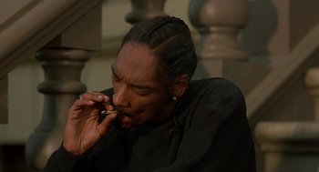 Movie still from “Half Baked” (1998), directed by Tamra Davis – A man sitting on the ground while using a cell phone; Close Up shot, High angle