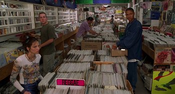 Movie still from “Half Baked” (1998), directed by Tamra Davis – A group of men standing in a room filled with lots of records; Wide shot, High angle
