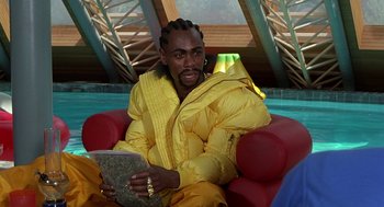 Movie still from “Half Baked” (1998), directed by Tamra Davis – A man sitting in a red chair wearing a yellow jacket; Close Up shot, High angle