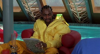 Movie still from “Half Baked” (1998), directed by Tamra Davis – A man sitting in a chair looking at something on a tablet computer; Medium shot, Overhead angle