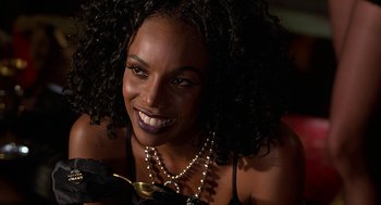 Movie still from “Half Baked” (1998), directed by Tamra Davis – A woman smiling while holding a gold dish in her hand; Close Up shot, Over the shoulder angle