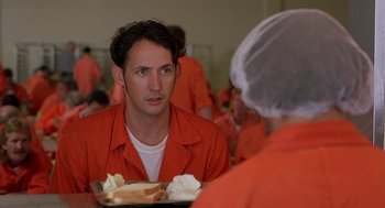 Movie still from “Half Baked” (1998), directed by Tamra Davis – A man wearing orange is sitting at a table with a plate of food; Close Up shot, Over the shoulder angle