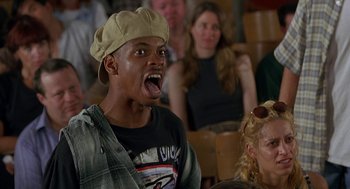Movie still from “Half Baked” (1998), directed by Tamra Davis – A man with a hat on and mouth wide open in front of a group of people; Medium shot, Low angle