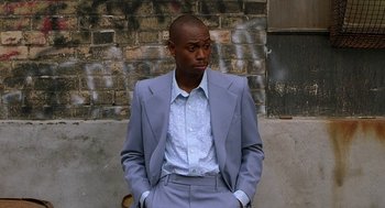Movie still from “Half Baked” (1998), directed by Tamra Davis – A man in a suit and tie standing in front of a brick wall; Medium shot, Low angle