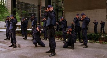 Movie still from “Half Baked” (1998), directed by Tamra Davis – A group of men in blue suits and hats are standing and kneeling; Wide shot, High angle