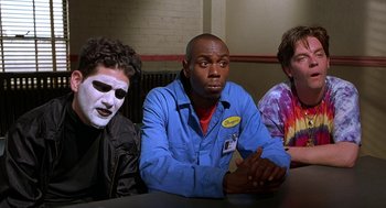 Movie still from “Half Baked” (1998), directed by Tamra Davis – A group of people sitting at a table with masks on; Medium shot, Over the shoulder angle