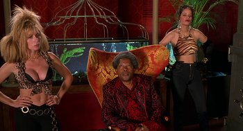 Movie still from “Half Baked” (1998), directed by Tamra Davis – A man sitting in a chair next to two women; Medium shot, Low angle