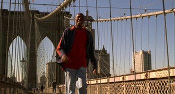 Movie still from “Half Baked” (1998), directed by Tamra Davis – A man is standing on a bridge with his arms outstreched; Wide shot, Low angle