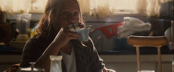 Movie still from “Halloween” (2007), directed by Rob Zombie – A woman sitting at a table drinking a cup of coffee; Medium shot, Over the shoulder angle